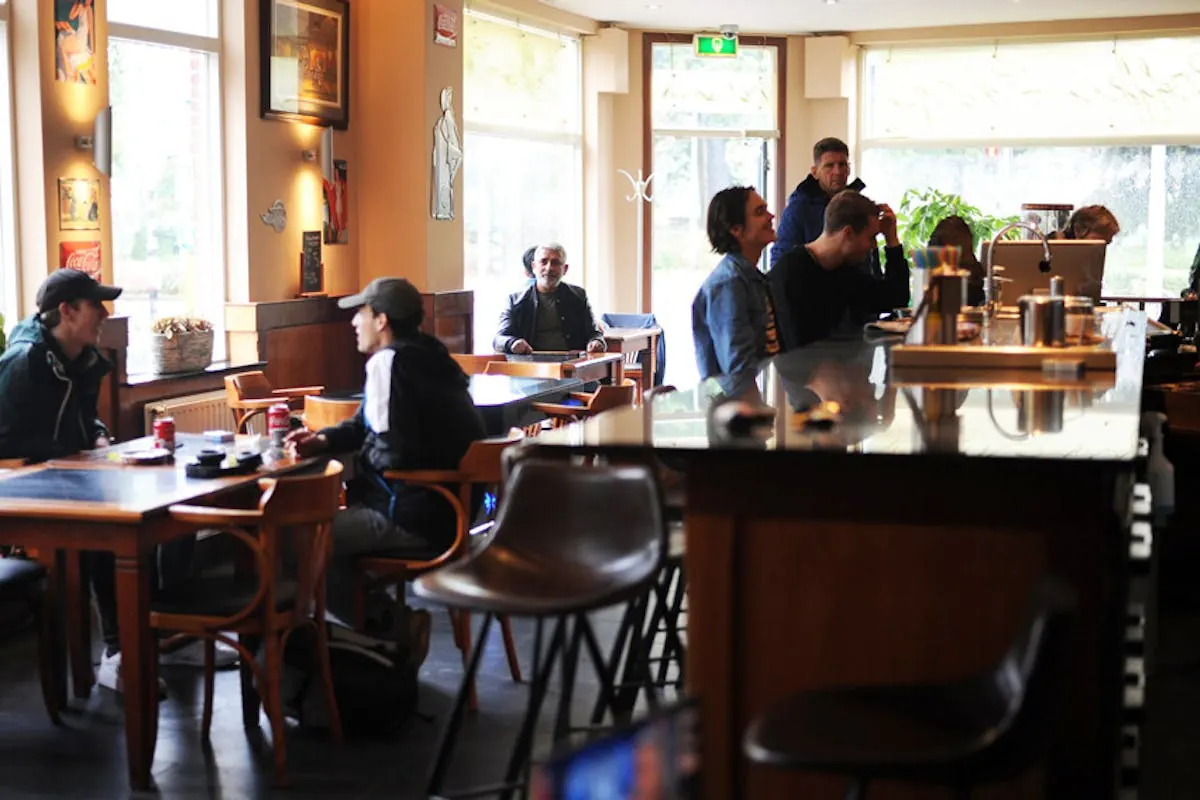 Interieur met gasten en bar bij Coffeeshop De Wedren in Nijmegen